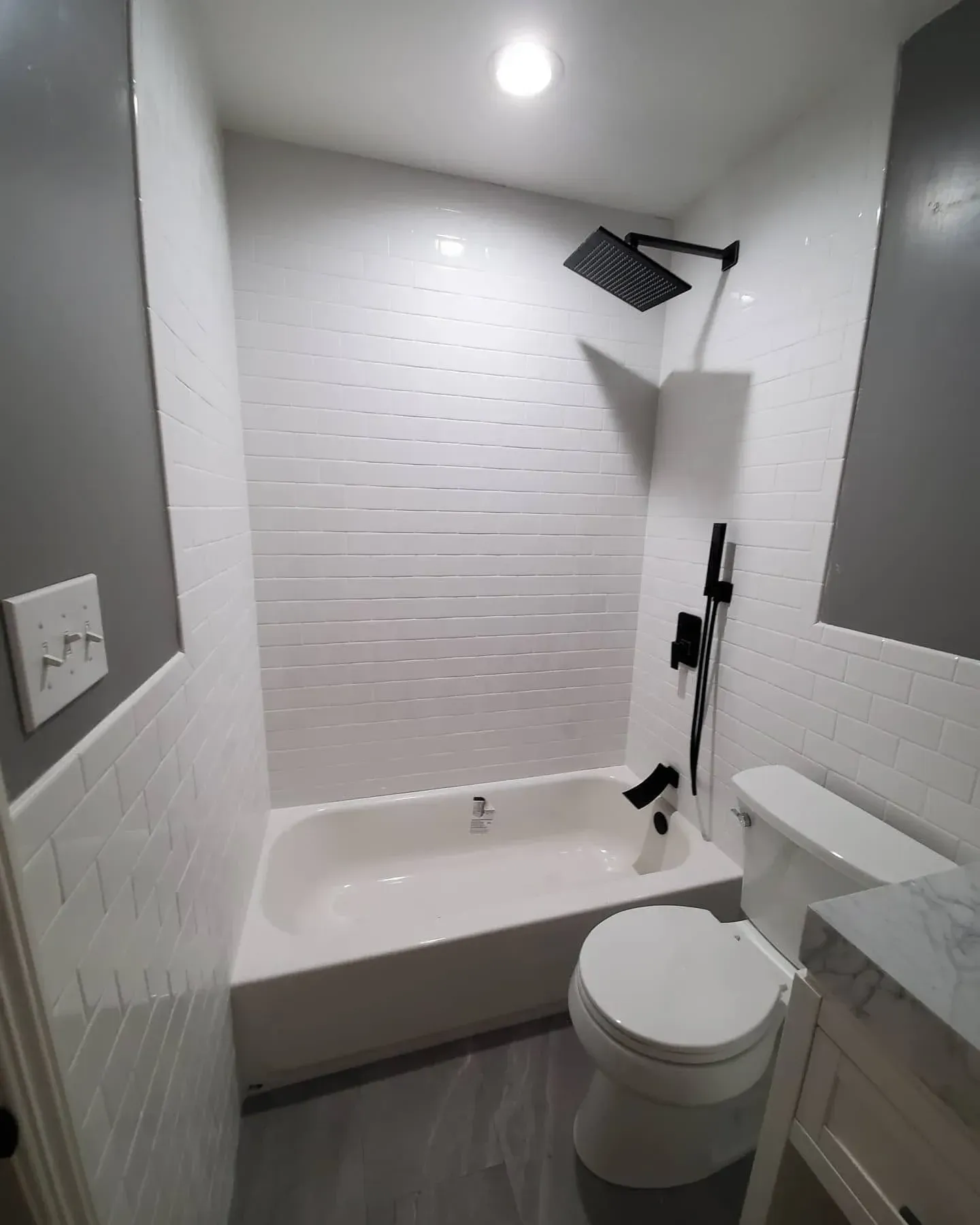 Small white bathroom with a bathtub, toilet, shower, and gray flooring. Small white bathroom with a bathtub, toilet, shower, and gray flooring.