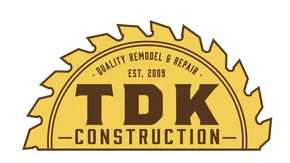 A yellow, semi-circular saw blade logo for TDK Construction, featuring the text 
