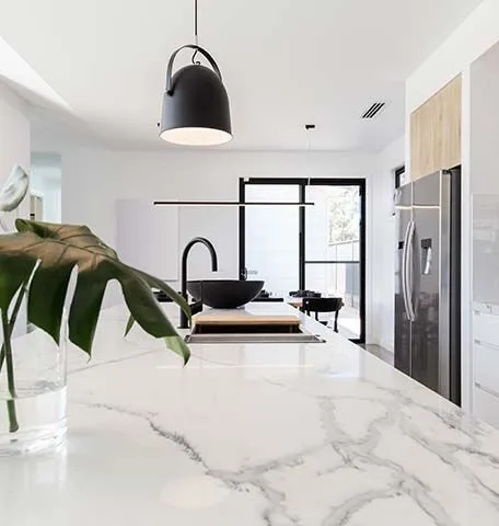 A modern kitchen with a white marble island, a black sink, and an aesthetic theme