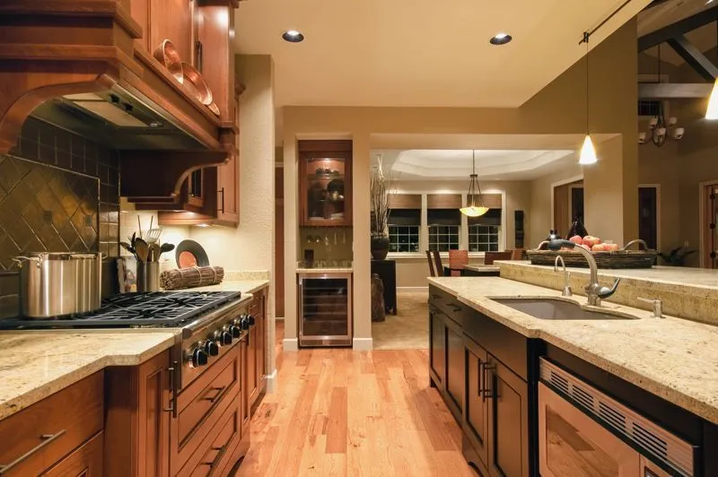 A luxury kitchen with wood cabinets, granite countertops, a gas range, a built-in wine cooler, and hardwood floors.