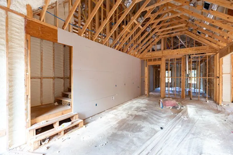 Interior of a building under construction featuring unfinished wooden roof trusses.