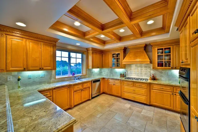 A bright, U-shaped kitchen features warm-toned wooden cabinets with lights.