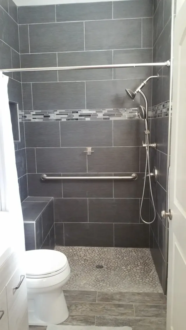 Small tiled bathroom with a toilet, shower, and gray wall tiles. Small tiled bathroom with a toilet, shower, and gray wall tiles.