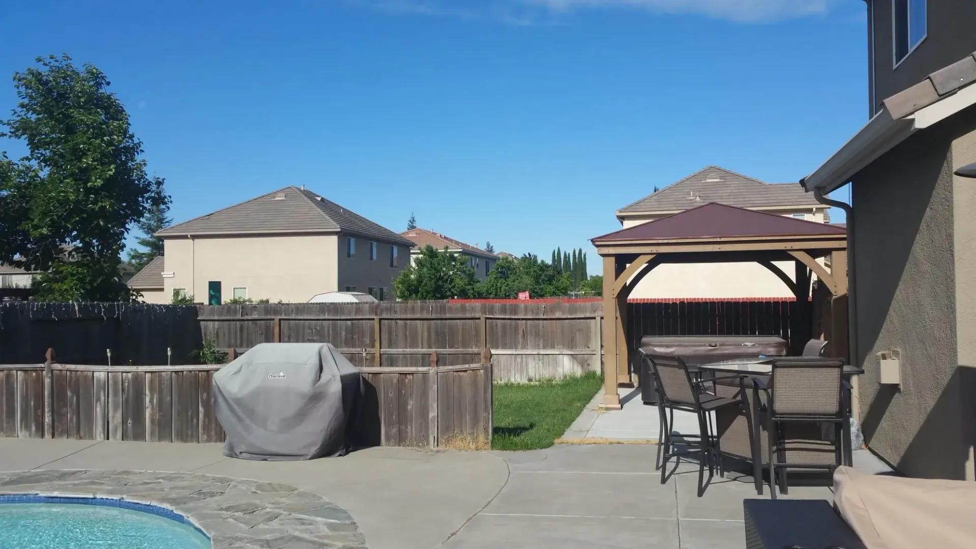 Residential patio beside a swimming pool with a gazebo, dining area, and covered grill in Galt, CA Residential patio beside a swimming pool with a gazebo, dining area, and covered grill in Galt, CA